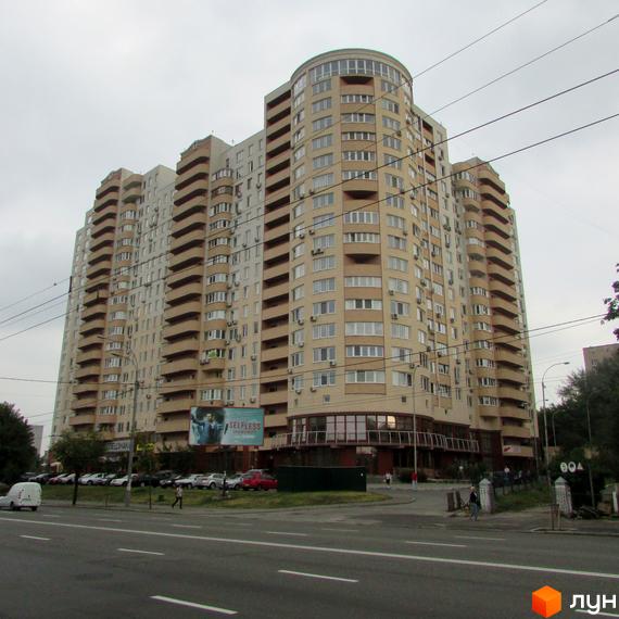 Будинок житлового комплексу Ново-Деміївський з великими вікнами та балконами, прибудинкова територія з паркувальними місцями.