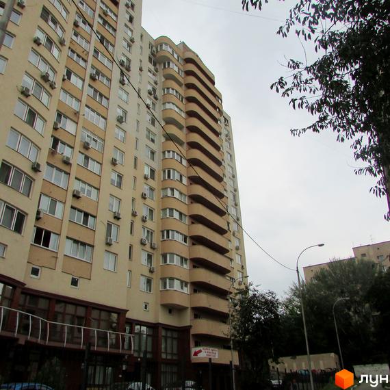 Житловий комплекс Ново-Деміївський з балконами та великими вікнами. Прибудинкова територія озеленена деревами та кущами.