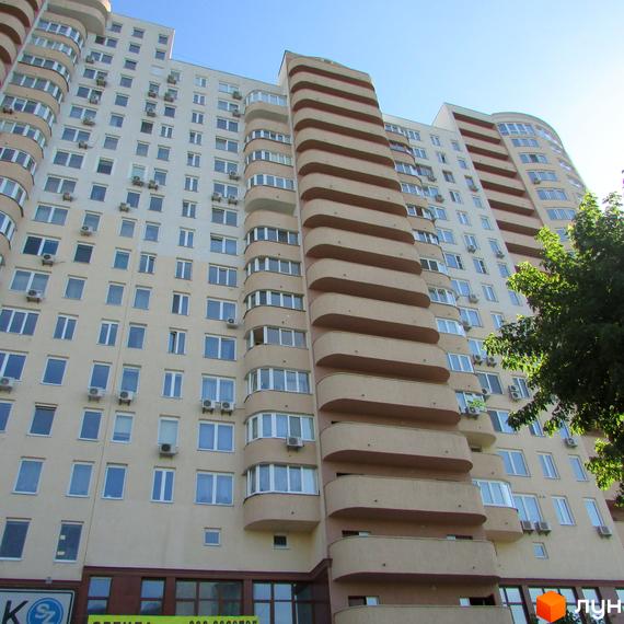 Вигляд житлового комплексу Ново-Деміївський з балконами та великими вікнами, прибудинкова територія з зеленими насадженнями.