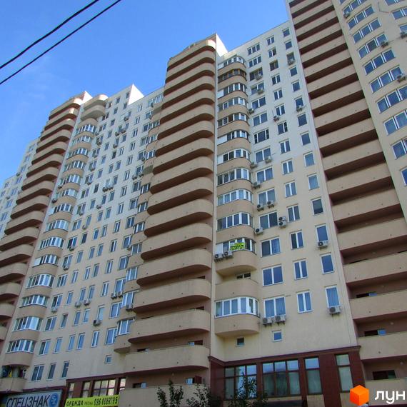 Житловий комплекс Ново-Деміївський, фасад будинку з балконами та вікнами, прибудинкова територія з зеленими насадженнями.