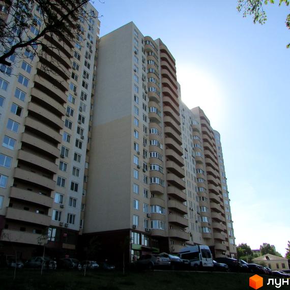 Житловий комплекс Ново-Деміївський з сучасними балконами та прибудинковою територією, де розташовані автомобілі.