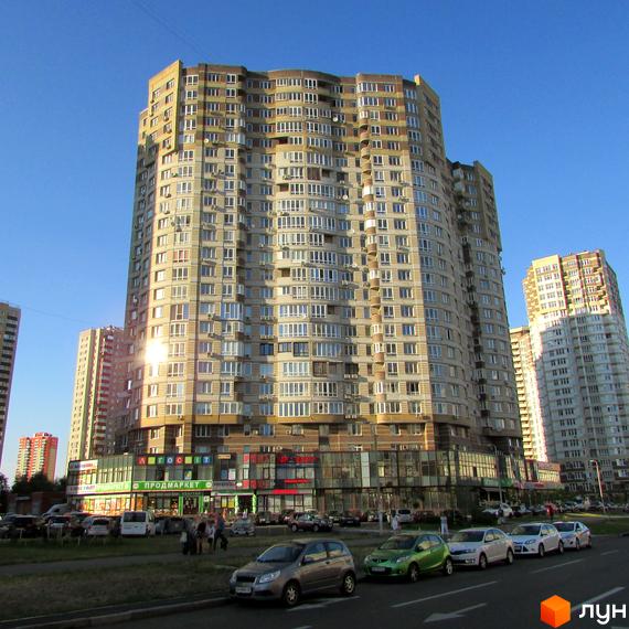 Житловий комплекс на вул. Ахматової, 30, з сучасним фасадом та прибудинковою територією з паркувальними місцями.