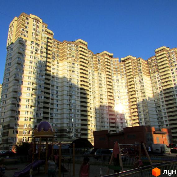 Житловий комплекс на вул. Ахматової, 30, з сучасною архітектурою та прибудинковою територією з дитячим майданчиком.