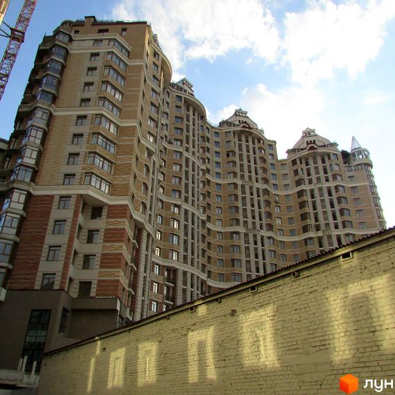 Житловий комплекс на вул. Богдана Хмельницького, 58а, з фасадом у світлих тонах та великою кількістю вікон. Прибудинкова територія облаштована для відпочинку.