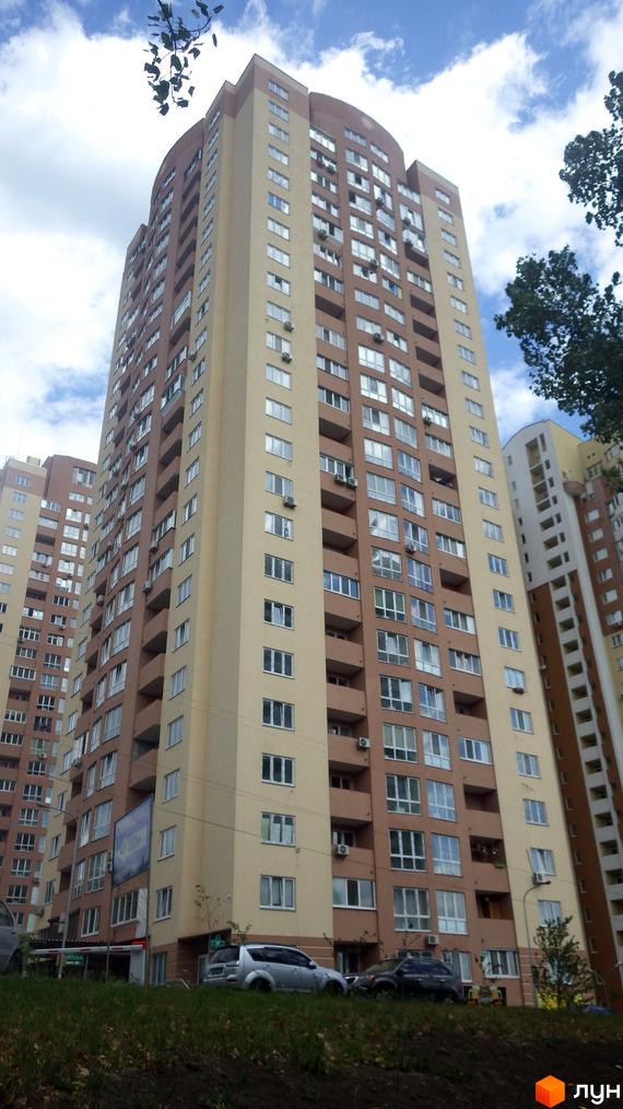 Житловий комплекс на пров. Моторний, 9, 9а. Високий будинок з балконами та прибудинковою територією, де паркуються автомобілі.