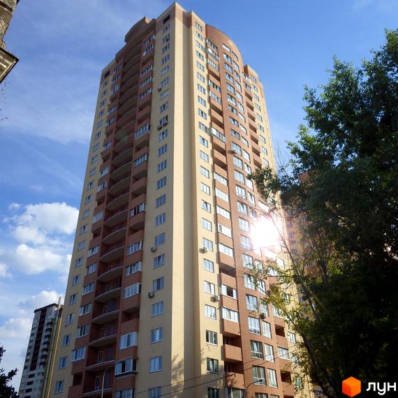 Висотний будинок на пров. Моторний, 9, 9а з балконами та великими вікнами, оточений зеленими насадженнями.