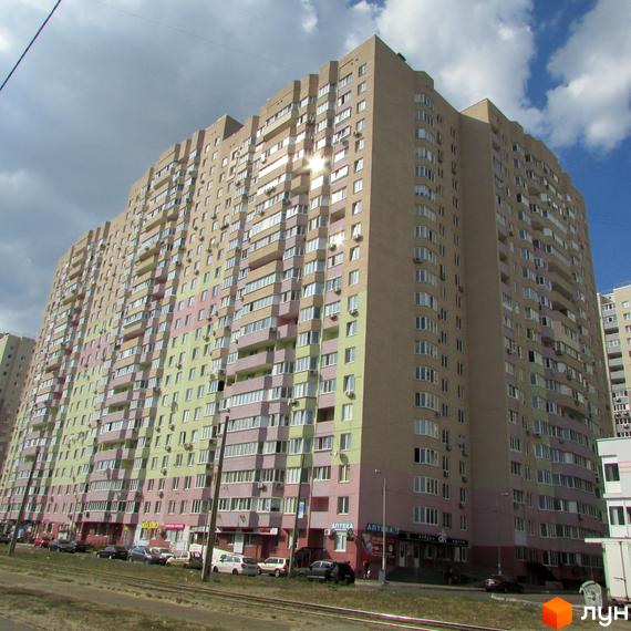 Житловий комплекс Милославичі з фасадом у світлих тонах та вітринами. Прибудинкова територія з автомобілями та зеленими насадженнями.