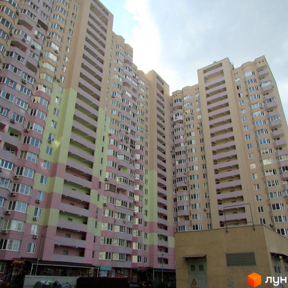 Житловий комплекс Милославичі з фасадом у світлих тонах та балконами. Прибудинкова територія з парковкою та зеленими насадженнями.