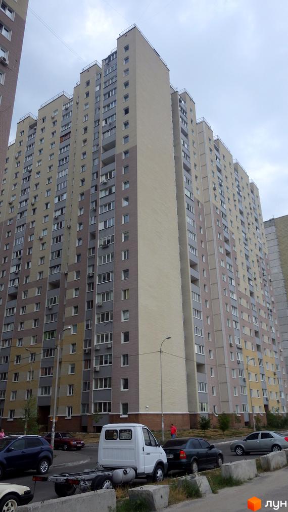 Багатоповерховий будинок Житлового комплексу Милославичі з різнокольоровими фасадами. На прибудинковій території припарковані автомобілі.