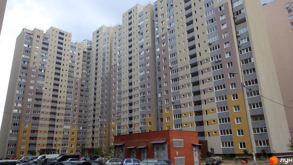 Житловий комплекс Милославичі з сучасними багатоповерхівками та прибудинковою територією, де розташовані автомобілі.