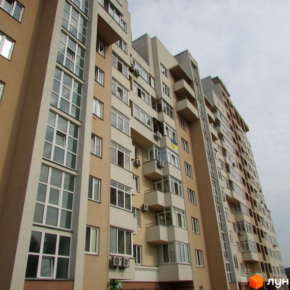 Житловий комплекс на вул. Петропавлівська, 50, 50б, з сучасним фасадом та великими вікнами. Прибудинкова територія озеленена та облаштована.