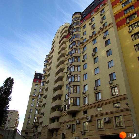 Житловий комплекс Златоустівський - висотна будівля з балконами та кондиціонерами на фасаді. Навколо будинку видно сусідні будівлі та дерева.