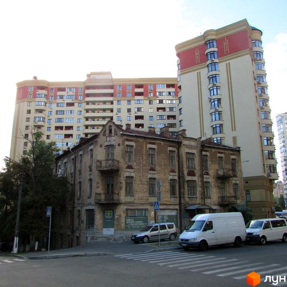 Зовнішній вигляд житлового комплексу ЖК Златоустівський з новими та старими будівлями на фоні. На передньому плані дорога з пішохідним переходом та автомобілями.