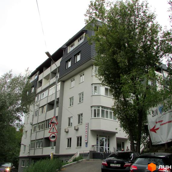 Житловий комплекс Віконт – багатоповерховий будинок світло-сірого кольору з темним дахом та балконами. Навколо будинку дерева та прибудинкова територія.