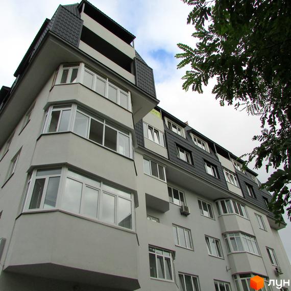 Житловий комплекс Віконт - фасадна частина будівлі з еркерними вікнами та балконами під сірим скатним дахом. Навколо зелені дерева.