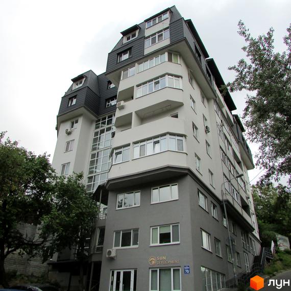 Житловий комплекс Віконт - багатоповерхова новобудова з сірим та білим фасадом, великою кількістю вікон та мансардним дахом. Поруч зелені дерева.