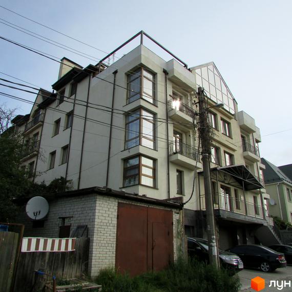 Зовнішній вигляд житлового комплексу Арт Хаус з балконами та великими вікнами. Прибудинкова територія з автомобілями та зеленими насадженнями.