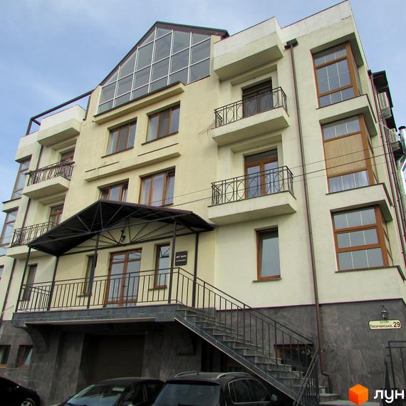 Житловий комплекс Арт Хаус з фасадом світлого кольору та балконами. Прибудинкова територія з парковкою та сходами.