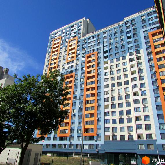 Житловий комплекс Богатирський - багатоповерховий будинок з яскравим фасадом у блакитних та помаранчевих тонах. Навколо будинку зелені дерева та невелика прибудинкова територія.