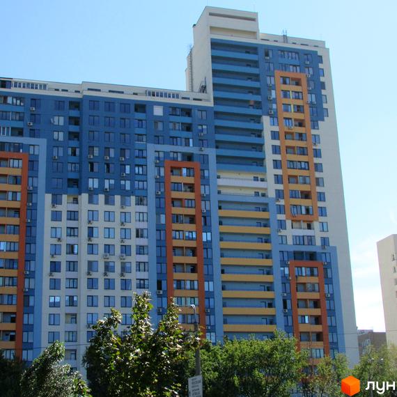 Житловий комплекс Богатирський - багатоповерховий будинок з яскравим фасадом у синьо-жовтих тонах. Навколо комплексу зелені дерева.