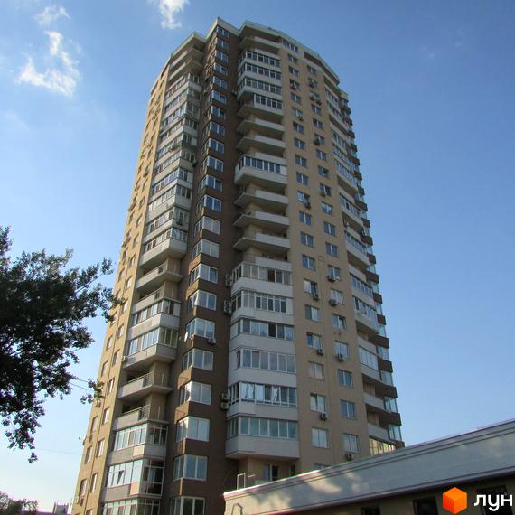 Висотна новобудова на вул. Ушинського, 14б з численними балконами та кондиціонерами на фасаді. Будинок має коричнево-бежеве оздоблення та великі вікна.
