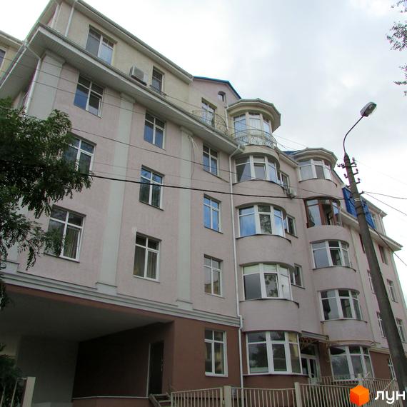 Фасад житлового комплексу на пров. Іллі Рєпіна (Шишкінський) з еркерними вікнами та балконами. Будинок має світло-бежевий колір стін та коричневий цоколь.