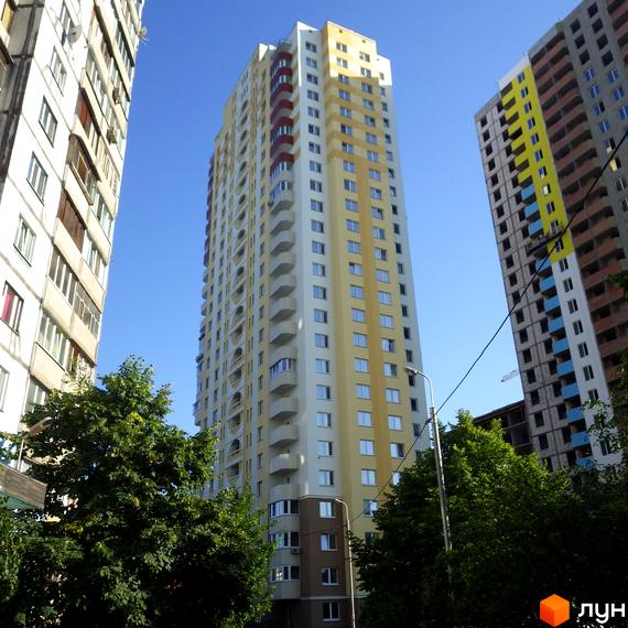 Високоповерховий житловий комплекс на вулиці Хорольській, 1а, з жовтим та білим фасадом, балконами та вікнами. Навколо зелені дерева та блакитне небо.