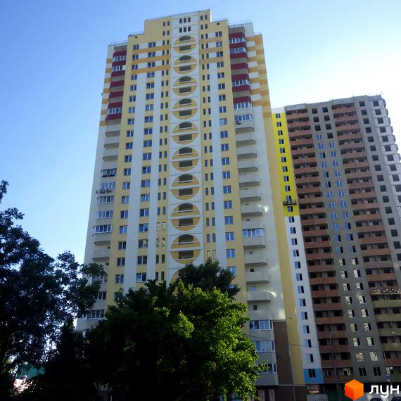 Високоповерховий житловий комплекс на вулиці Хорольська, 1а. Фасад будинку оздоблений жовтими та білими панелями з червоними вставками та круглими вікнами.