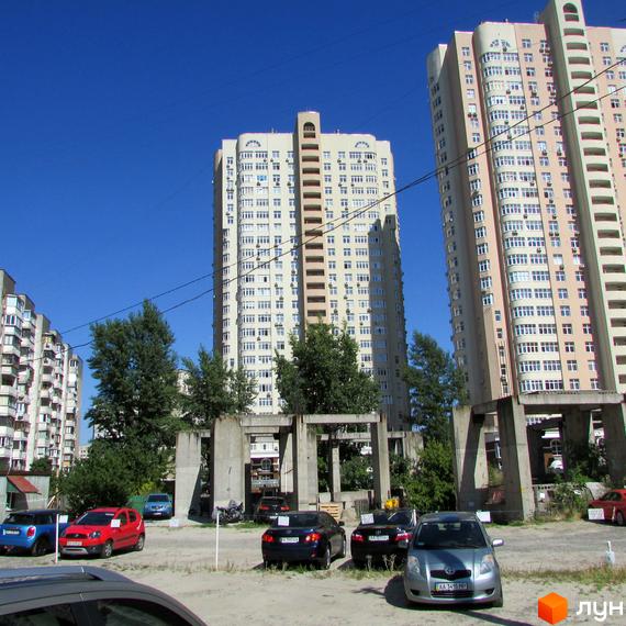 Будівельний проєкт на вул. Драгоманова (будмайданчики 1, 2, 3) з високими світлими багатоповерховими будинками та прибудинковою територією з автомобілями та зеленими насадженнями.