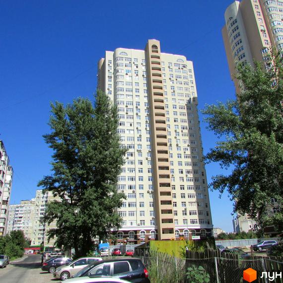 Висотна новобудова на вулиці Драгоманова, 1, 2, 3. Зовнішній вигляд будинку з численними вікнами та балконами. Прибудинкова територія з деревами та припаркованими автомобілями.