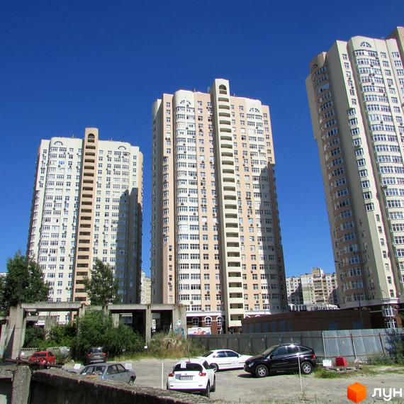 Високоповерхові новобудови на вул. Драгоманова, будмайданчики 1, 2, 3. Навколо будівельний майданчик з парканом та автомобілями.