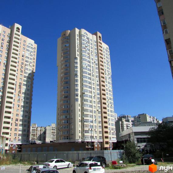 Високі світлі новобудови на вулиці Драгоманова. Навколо будівельні майданчики та припарковані автомобілі.