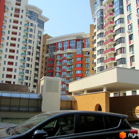 Житловий комплекс Сонячна брама з яскравими фасадами та прибудинковою територією. Вид на парковку та архітектурні деталі будівель.