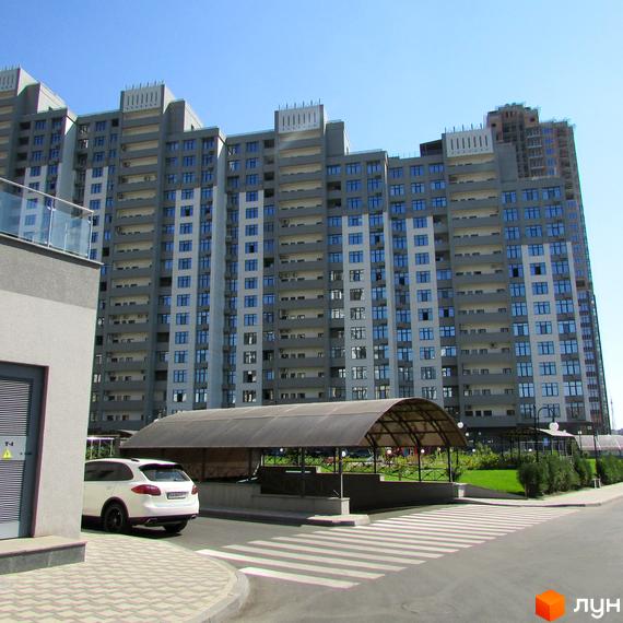 Багатоповерхові житлові будинки Житловий комплекс Новопечерські Липки з сірими фасадами та великою кількістю вікон. Перед будинками є критий паркінг та зелені зони.