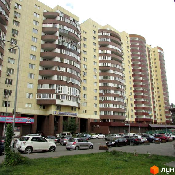 Багатоповерхові будинки Житлового комплексу Парковий з бежевими фасадами та коричневими балконами. Перед будинками розташований паркінг з автомобілями та зелена зона.