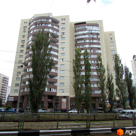 Житловий комплекс Парковий: багатоповерхова будівля зі світлим фасадом, коричневими балконами та комерційними приміщеннями на першому поверсі. Перед будинком ростуть високі дерева.