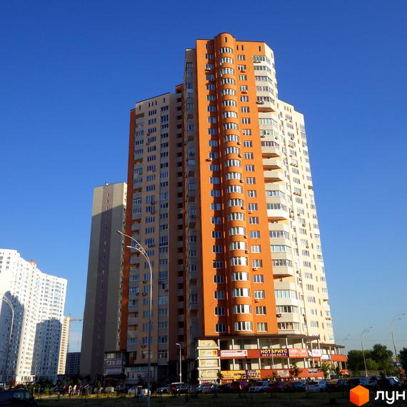 Житловий комплекс Молодіжний квартал з висотним будинком та прибудинковою територією. На передньому плані видно магазини та автомобілі.