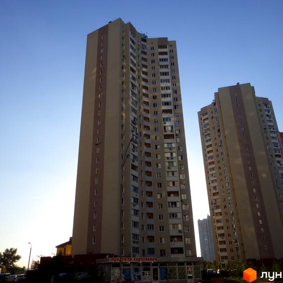 Житловий комплекс Молодіжний квартал з двома високими будинками. Прибудинкова територія з зеленими насадженнями та паркувальними місцями.