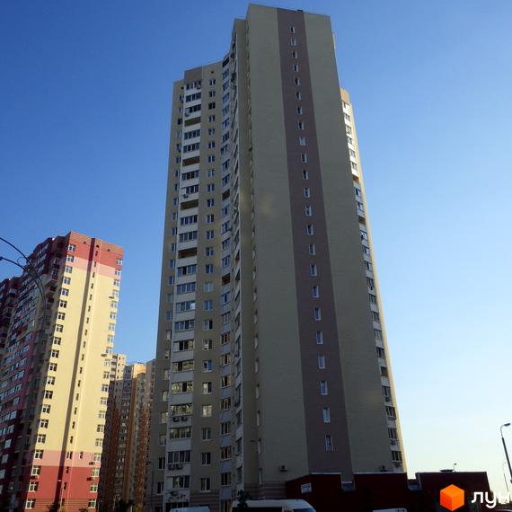 Вид на багатоповерховий будинок житлового комплексу Молодіжний квартал з прибудинковою територією та ясним небом.