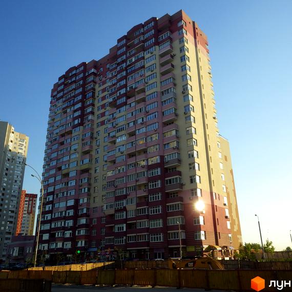 Житловий комплекс Молодіжний квартал з фасадом у світлих тонах та великими вікнами. На передньому плані прибудинкова територія з будівельною технікою.