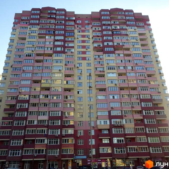 Житловий комплекс Молодіжний квартал з яскравим фасадом та великими вікнами. Прибудинкова територія з магазинами на першому поверсі.