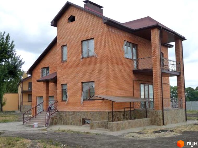 Цегляний двоповерховий будинок з балконом та терасою. На території розташовані сходи з металевими поручнями та невелика ділянка.