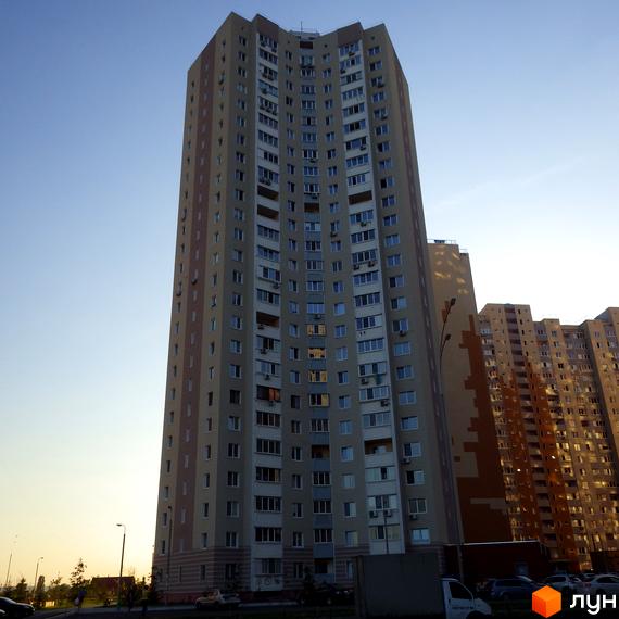 Житловий комплекс Молодіжний квартал з висотним будинком та прибудинковою територією. Вид на фасад з великими вікнами.