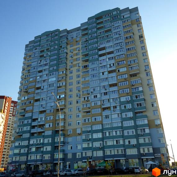 Житловий комплекс Молодіжний квартал з фасадом у світлих тонах та великими вікнами. Прибудинкова територія з паркувальними місцями.