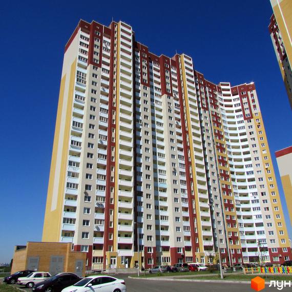 Житловий комплекс Молодіжний квартал з висотними будинками та прибудинковою територією. На передньому плані автомобілі та зелена зона.