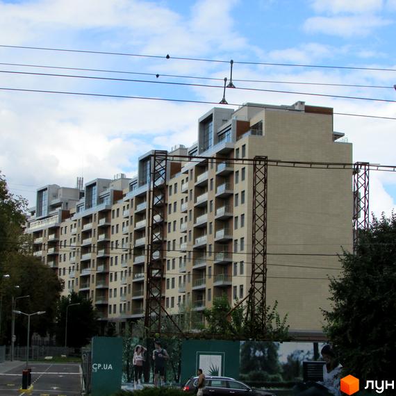 Житловий комплекс Crystal Park з фасадом з світлого матеріалу та балконами. Прибудинкова територія озеленена деревами та кущами.