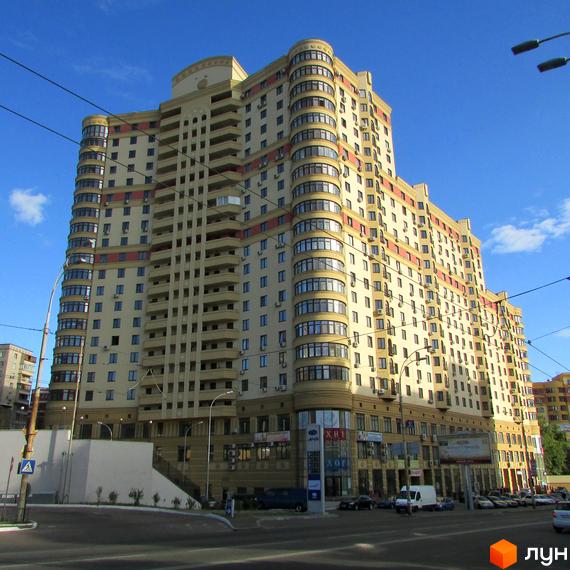 Житловий комплекс Златоустівський - висотна будівля кремового кольору з вигнутими фасадами та балконами. Навколо будівлі розташована міська вулиця з автомобілями та пішохідними зонами.