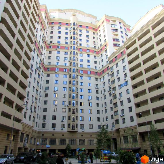 Зовнішній вигляд житлового комплексу Златоустівський з багатоповерховими будинками та балконами. На прибудинковій території видно дитячий майданчик та дерева.