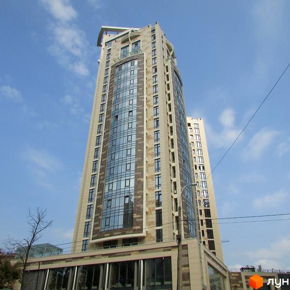 Житловий комплекс Бульвар Фонтанів з сучасним фасадом та великими вікнами. Прибудинкова територія облаштована зеленими насадженнями.