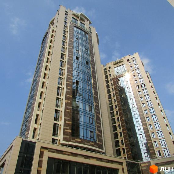 Вид на житловий комплекс Бульвар Фонтанів з великими вікнами та сучасним фасадом, оточений зеленими насадженнями.